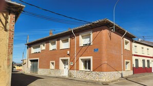Un edificio a due piani con base in pietra e livelli superiori in mattoni rossi, caratterizzato da numerose finestre e un'ingresso ben visibile.