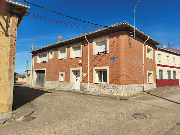 Un edificio de dos plantas con base de piedra, varias ventanas y un cartel que dice 'Calle Traviesa'.