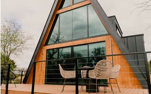 A modern building with large windows, a wooden exterior, and outdoor seating. - NEW | The Pedernales A-Frame (Fredericksburg)
