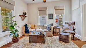 A living room with a sofa, armchair, coffee table, and a ceiling fan. - “Henry’s Haus” | Walk to Main | Pet Friendly! (Fredericksburg)
