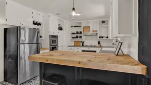 Een moderne keuken met witte kasten, roestvrijstalen apparatuur en een houten eiland.