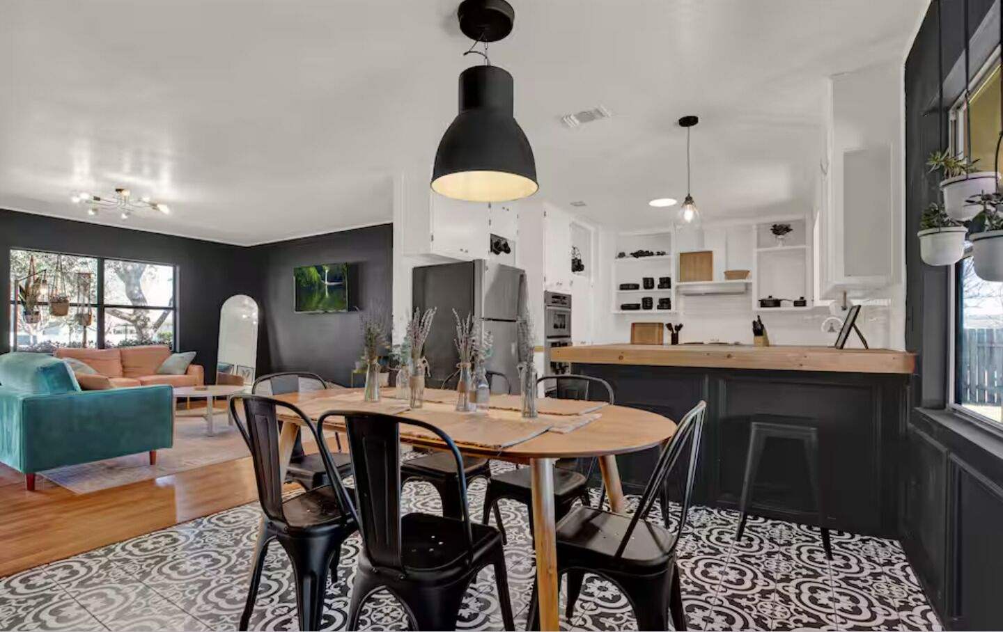 Una cucina moderna con isola centrale, una zona pranzo con tavolo rotondo e un soggiorno con divano color petrolio.