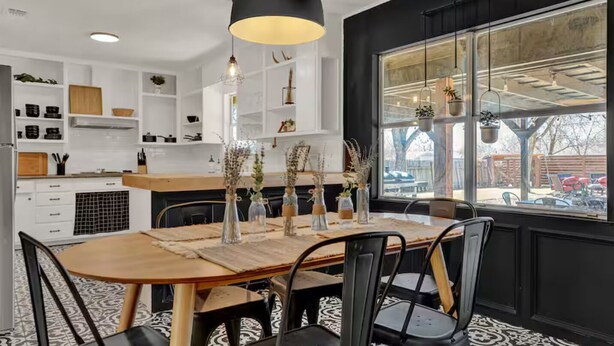 Een moderne keuken met witte kasten, een houten eettafel en zwarte stoelen.