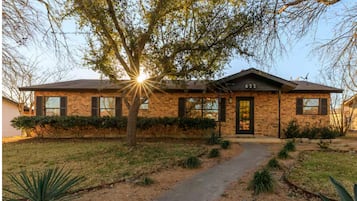 A brick house with a number '622' on the front, a tree in front, and a pathway leading to the entrance.