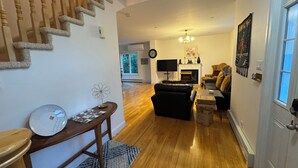 Uma sala de estar com lareira, sofá, mesa de centro e escada.