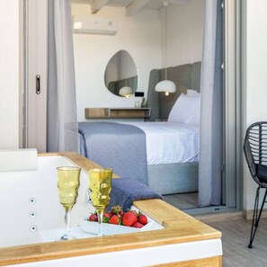 Ein Schlafzimmer mit einem Bett, einem Nachttisch mit Gläsern und Erdbeeren sowie einem Stuhl.