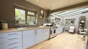 A modern kitchen with a large island, built-in oven, and ample natural light from skylights. - St Davids by NewFo dot Rest (Milford on Sea)