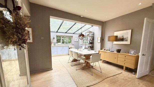 A spacious kitchen with a large island, a dining area with a table and chairs, and a view through a glass door to an outdoor area. - St Davids by NewFo dot Rest (Milford on Sea)