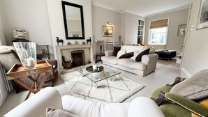 A living room with a fireplace, a sofa, a coffee table, and a bookshelf. - St Davids by NewFo dot Rest (Milford on Sea)