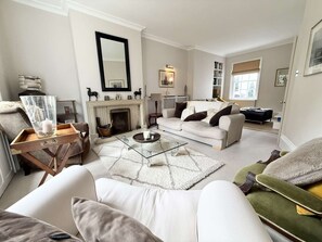 Ein Wohnzimmer mit Kamin, einer Couch, einem Couchtisch und einem Bücherregal.