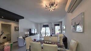 A modern living room with a dining area, a chandelier, and a television. - Groundfloor, oasis beach VI la zenia (La Zenia)