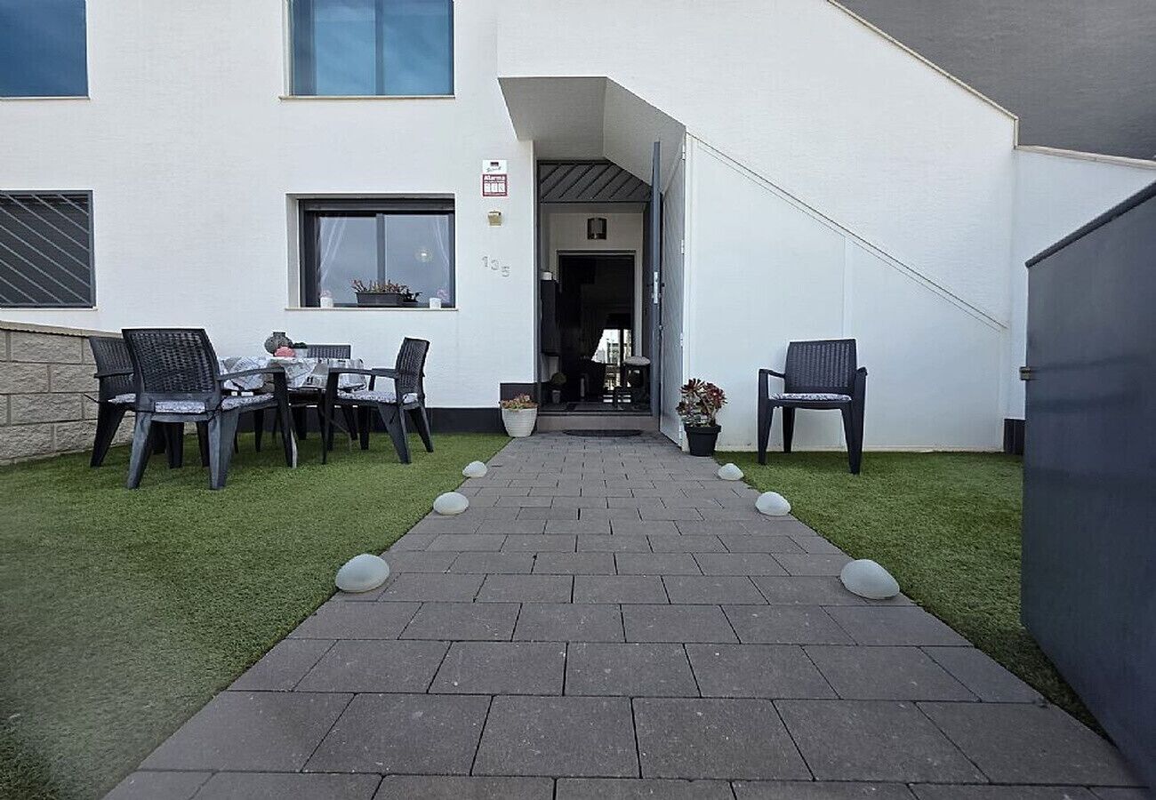 Een pad dat leidt naar een gebouw met terras en een deur.