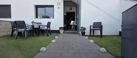 Een pad dat leidt naar een gebouw met terras en een deur.