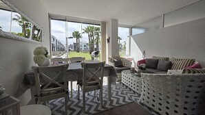 A modern interior with a dining area, a sofa, and a view of palm trees. - Groundfloor, oasis beach VI la zenia (La Zenia)