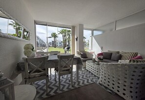 Ein modernes Interieur mit Essbereich, einer Couch und Blick auf Palmen.