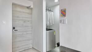 A modern bathroom with a wooden door, a washing machine, and a towel rack. - Cozy apartment, location to enjoy the beautiful Cartagena/Colombia. (Cartagena de Indias)