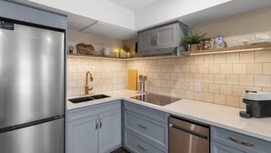 A modern kitchen with stainless steel appliances, grey cabinetry, a built-in dishwasher, and a tiled backsplash. - Upper Mission Casita | Boutique Lakeview Suite for Business or Leisure (Kelowna)