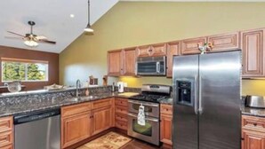 Una cocina moderna con armarios de madera, electrodomésticos de acero inoxidable, lavavajillas y ventilador de techo.