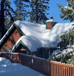 A cabin with a snow-covered roof, surrounded by trees and a wooden fence. - Private 3 -bedroom house in delightful Lake Arrowhead,  with AC comfort (Lake Arrowhead)