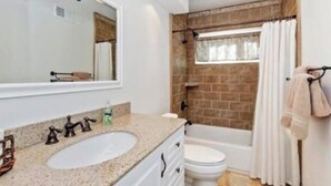 Un baño con lavamanos, espejo y bañera.