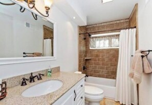 Ein Badezimmer mit Waschbecken, Spiegel und Badewanne.