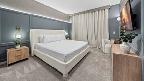 Una camera da letto moderna con un letto grande, comodini, una TV e una scrivania con una pianta.