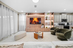 A modern living room with a flat-screen TV, a sofa, a coffee table, and a fireplace. - 7BR house with game room near Disney area (Kissimmee)