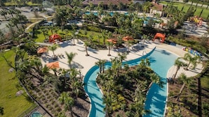 A resort with a large swimming pool, palm trees, and a view of surrounding houses. - 5BR house with game room near Disney area (Davenport)