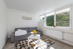 Ein modernes Wohnzimmer mit einem grauen Sofa, einem weißen Couchtisch und einem gemusterten Teppich.
