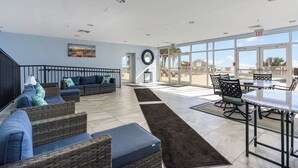 A spacious indoor area with a large window, a staircase, and a seating area with wicker furniture. - TOP Floor 2bd/2ba Oceanfront Master w Free Wi-fi (Myrtle Beach)