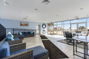 A spacious indoor area with a large window, a staircase, and a seating area with wicker furniture. - TOP Floor 2bd/2ba Oceanfront Master w Free Wi-fi (Myrtle Beach)