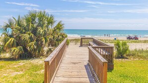 A wooden boardwalk leading to a beach with palm trees and a clear blue sky. - TOP Floor 2bd/2ba Oceanfront Master w Free Wi-fi (Myrtle Beach)