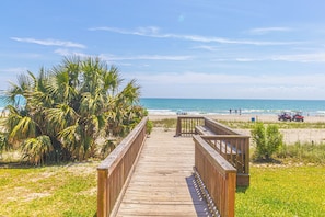 A wooden boardwalk leading to a beach with palm trees and a clear blue sky. - TOP Floor 2bd/2ba Oceanfront Master w Free Wi-fi (Myrtle Beach)