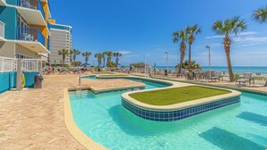 A swimming pool area with multiple sections, palm trees, and a view of the ocean. - TOP Floor 2bd/2ba Oceanfront Master w Free Wi-fi (Myrtle Beach)
