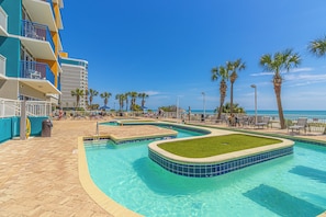 A swimming pool area with multiple sections, palm trees, and a view of the ocean. - TOP Floor 2bd/2ba Oceanfront Master w Free Wi-fi (Myrtle Beach)