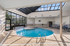 Una piscina interior con paredes de vidrio transparente, suelo de baldosas y techo cubierto.