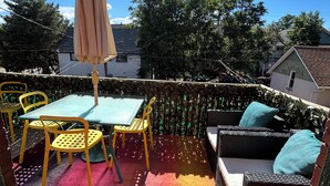 An outdoor patio with a table and chairs, a wicker sofa with cushions, and a hanging umbrella. - The Garden House on Emerson - Capitol Hill 2/1 walkable to down + parking + deck (Denver)