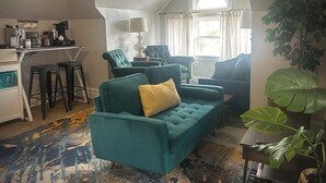 A cozy living room with a green sofa, a coffee station, and a large window with curtains. - The Garden House on Emerson - Capitol Hill 2/1 walkable to down + parking + deck (Denver)