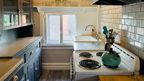 A kitchen with a stove, sink, cabinets, and a window. - The Garden House on Emerson - Capitol Hill 2/1 walkable to down + parking + deck (Denver)