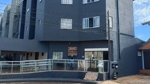 A multi-story building with a flat roof, large windows, and a sign indicating a residential area. - Residencial Wolverine  (Foz do Iguaçu)