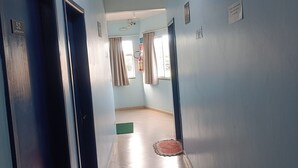 A hallway with light blue walls, a tiled floor, and doors leading to rooms. - Residencial Wolverine  (Foz do Iguaçu)