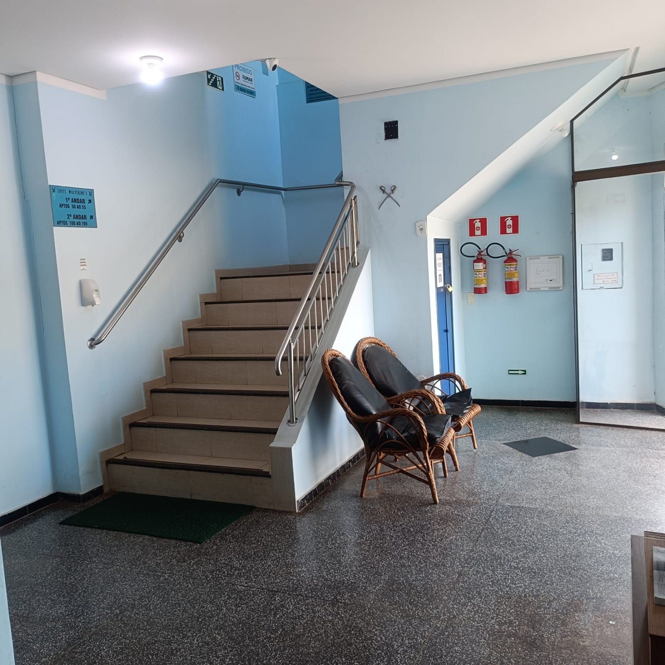 Una escalera con barandillas, un extintor y un letrero que indica una zona para fumadores.