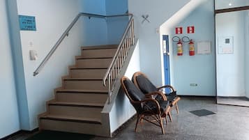 Una escalera con barandillas, un extintor y un letrero que indica una zona para fumadores.