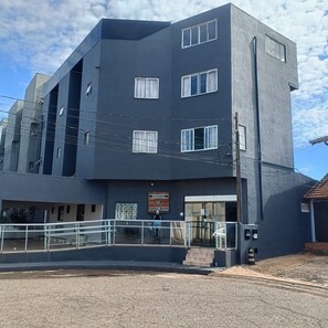 Un edificio de varios pisos con techo plano, ventanas amplias y un letrero que indica una zona residencial.