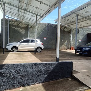 Un área de estacionamiento techada con un coche blanco y un coche azul aparcados.