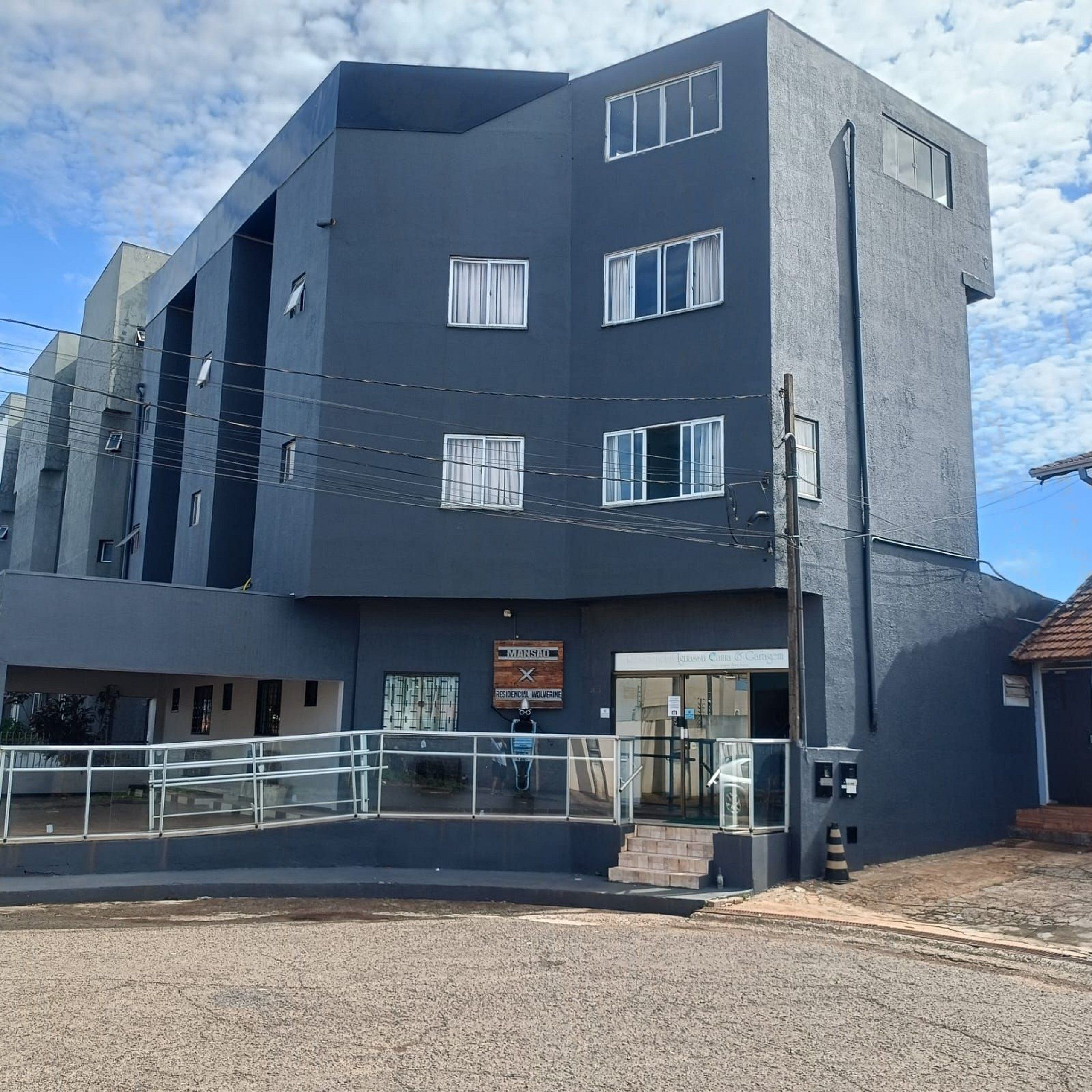 A multi-story building with a flat roof, large windows, and a sign indicating a residential area.