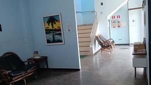 A room with a wooden chair, a small table, a framed picture on the wall, and a staircase leading to another area. - Residencial Wolverine  (Foz do Iguaçu)