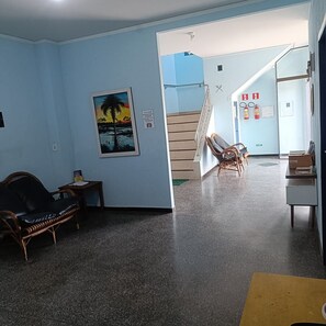 A room with a wooden chair, a small table, a framed picture on the wall, and a staircase leading to another area. - Residencial Wolverine  (Foz do Iguaçu)