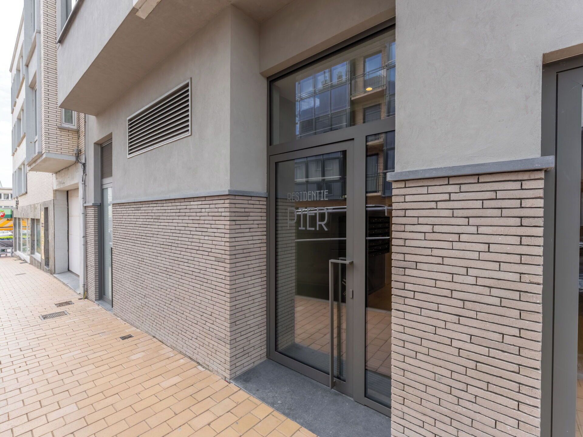 Un edificio moderno con fachada de ladrillo, entrada de vidrio y un letrero que dice 'RESIDENTIE'.