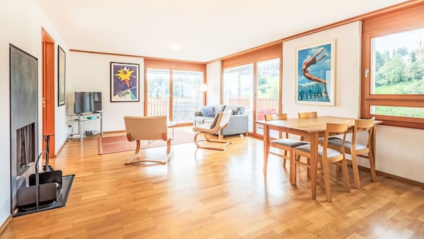 Un salón espacioso con piso de madera, una mesa de comedor, un sofá y un televisor.